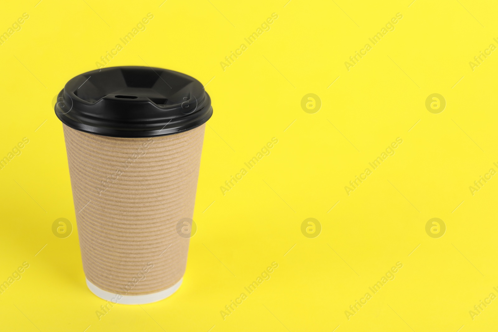 Photo of Paper cup with plastic lid on yellow background, space for text. Coffee to go