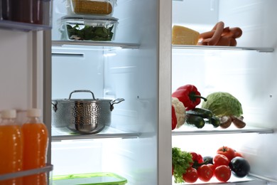 Photo of Open refrigerator full of different products indoors