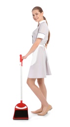 Young chambermaid with broom and dustpan on white background