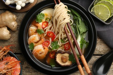 Flat lay composition with delicious ramen in bowl and ingredients on wooden table. Noodle soup