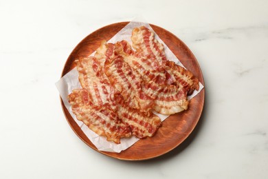 Photo of Delicious fried bacon slices on white marble table, top view