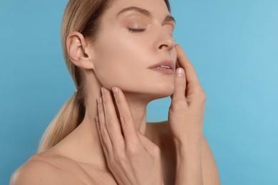 Photo of Woman massaging her face on turquoise background