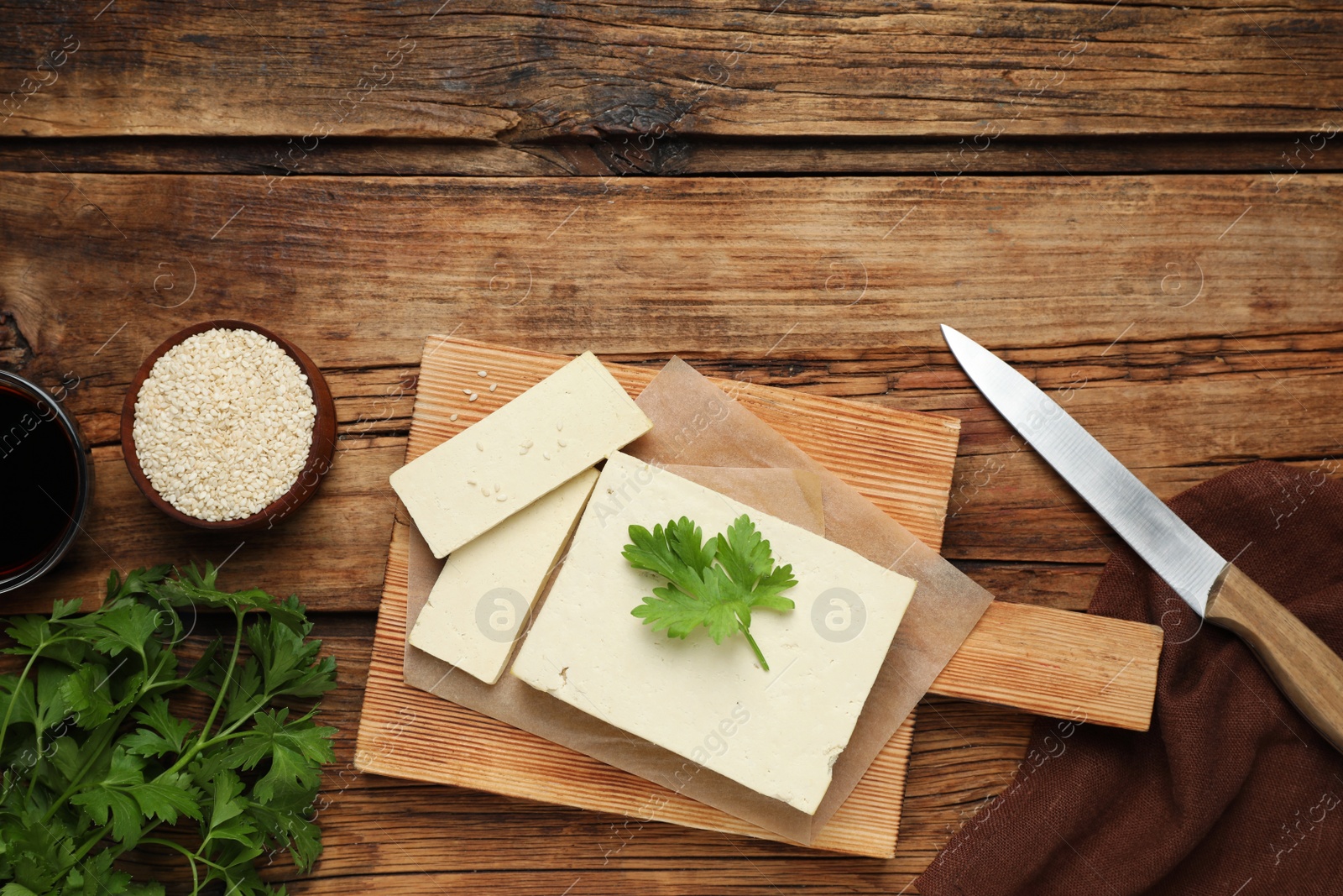 Photo of Delicious tofu with parsley served on wooden table, flat lay