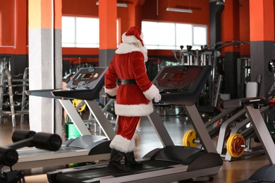 Photo of Authentic Santa Claus training on treadmill in modern gym