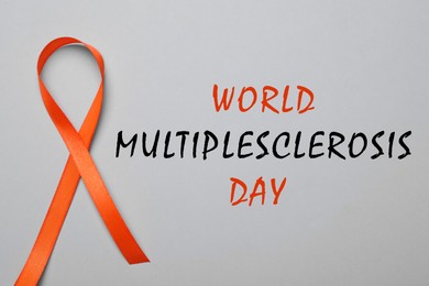 Image of Multiple Sclerosis Awareness Day. Orange ribbon on grey background, top view