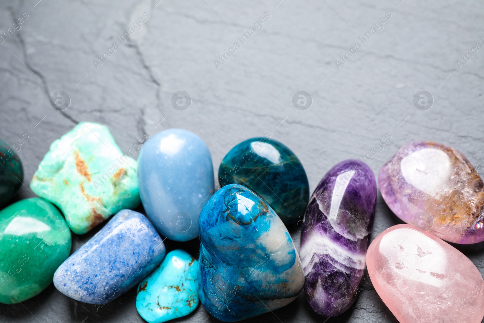 Photo of Row of different beautiful gemstones on grey background