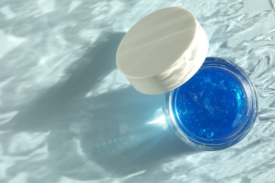 Photo of Open jar of cosmetic product on light blue background, top view. Space for text