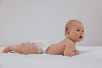Cute little baby in diaper lying on bed