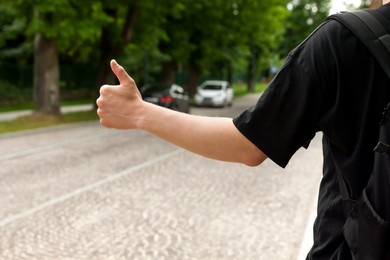 Photo of Man catching car on road, closeup. Hitchhiking trip