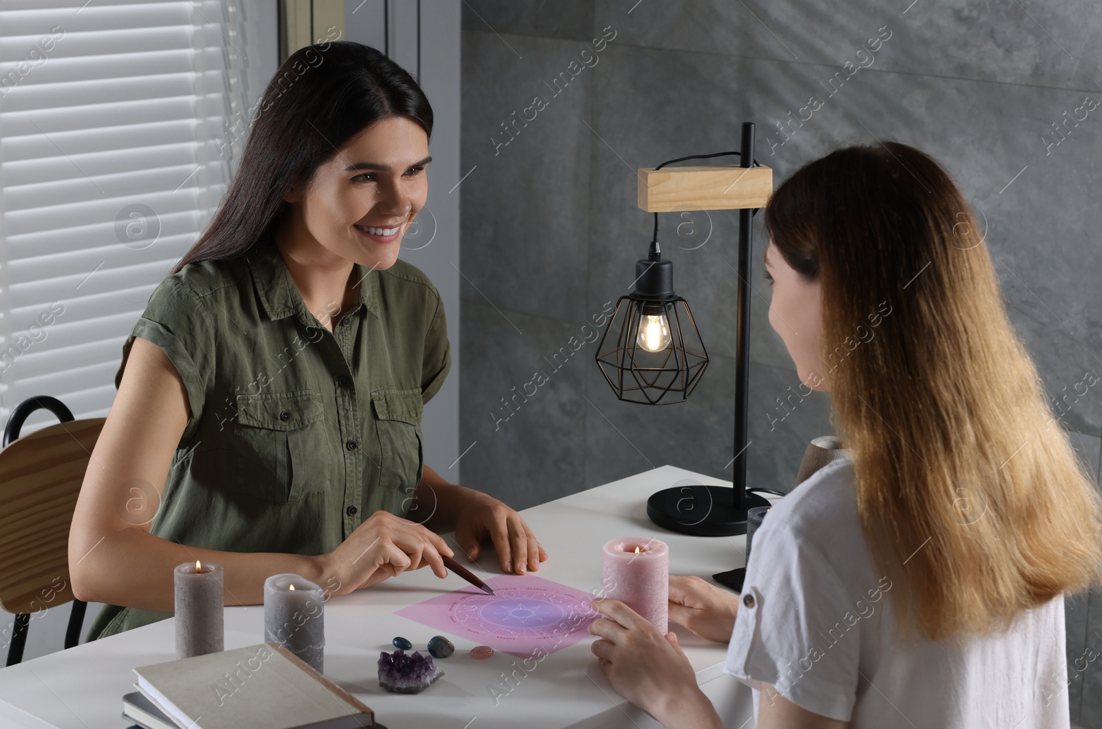 Photo of Astrologer showing zodiac wheel to client at table indoors