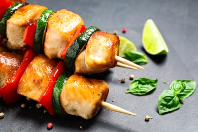 Delicious chicken shish kebabs with vegetables on black table, closeup