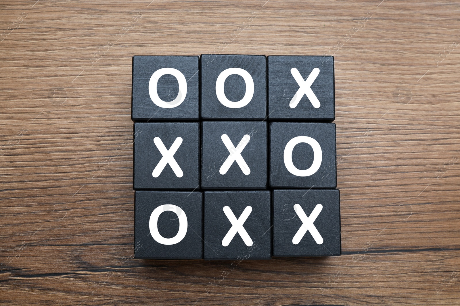 Photo of Tic tac toe cube set on wooden table, flat lay