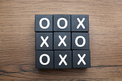 Tic tac toe cube set on wooden table, flat lay