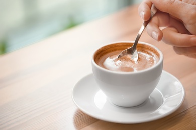 Woman with cup of aromatic coffee at wooden table