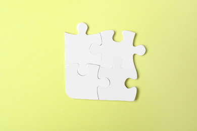 Photo of Blank white puzzle pieces on yellow background, top view