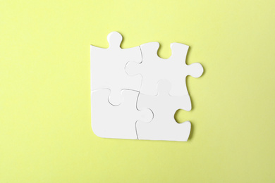 Blank white puzzle pieces on yellow background, top view