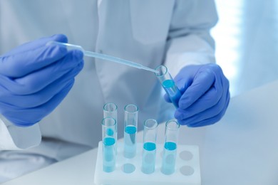 Scientist dripping sample into test tube in laboratory, closeup. Medical research