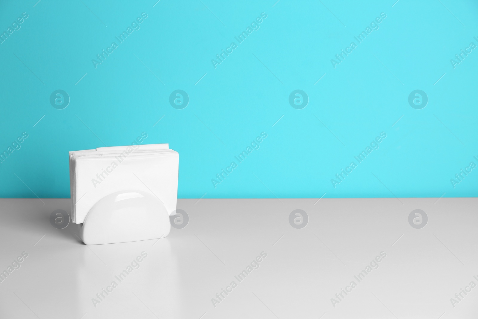 Photo of Ceramic napkin holder with paper serviettes on table. Space for text