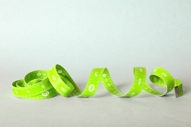 Photo of Green measuring tape on light background, closeup