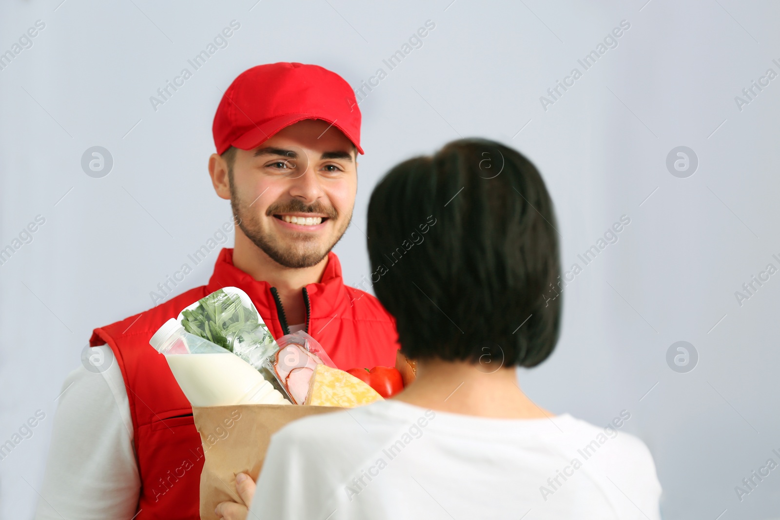 Photo of Male courier delivering food to client on light background