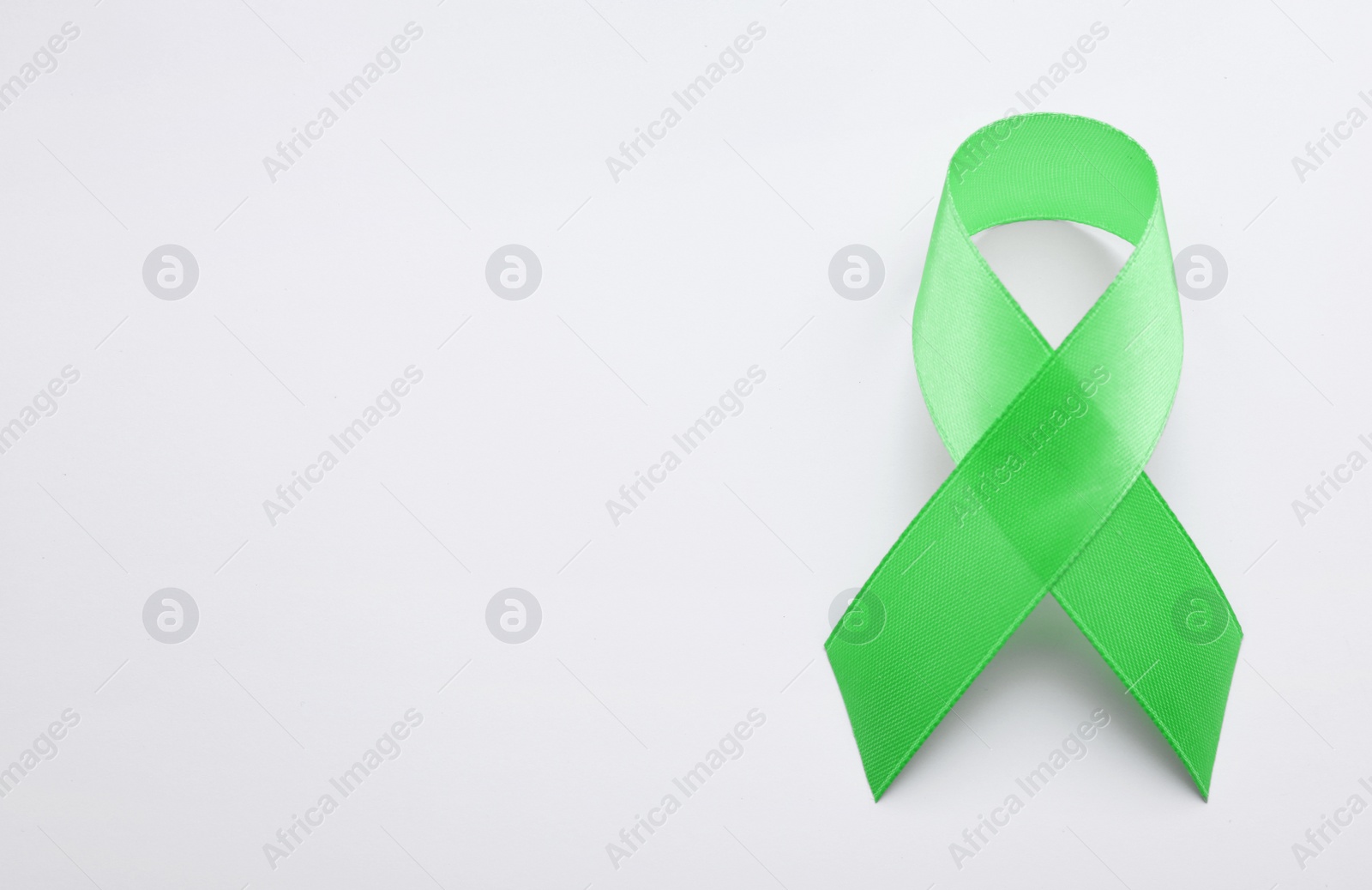 Photo of World Mental Health Day. Green ribbon on white background, top view with space for text