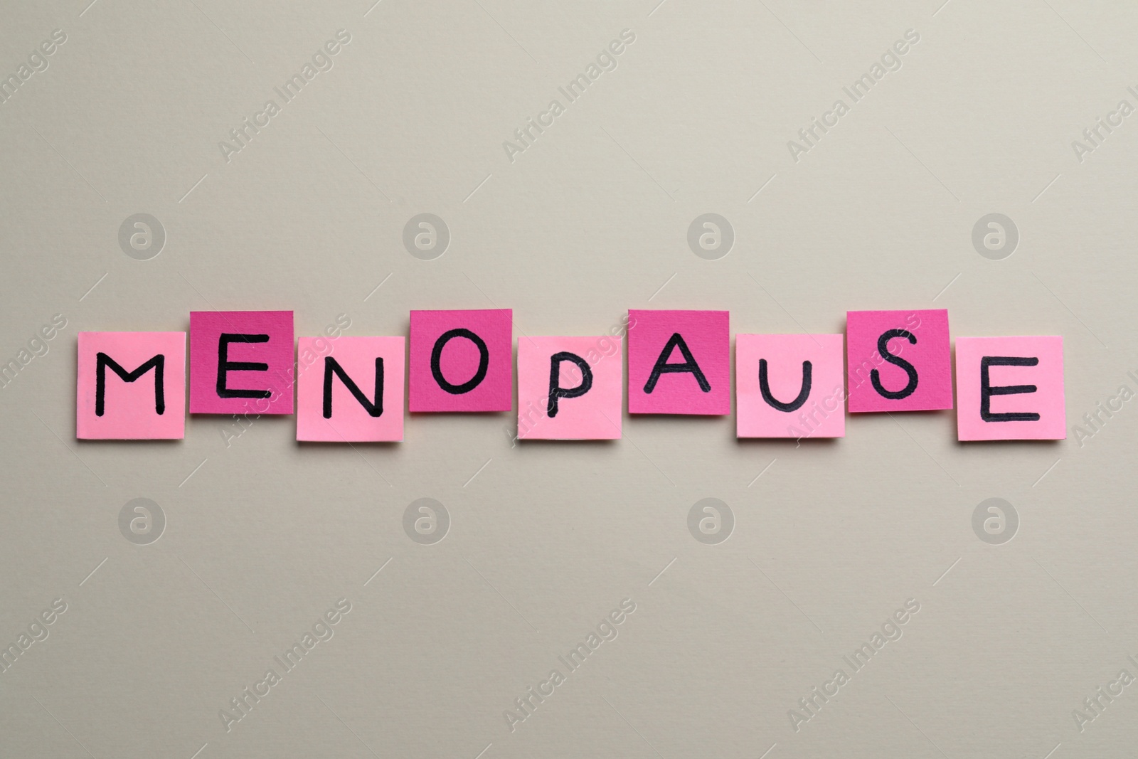 Photo of Pink paper notes with word Menopause on beige background, flat lay