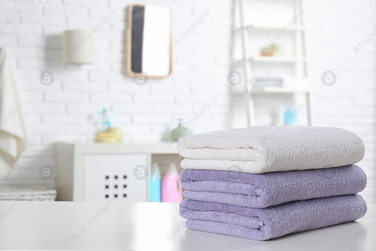 Photo of Stack of fresh towels on table in bathroom. Space for text