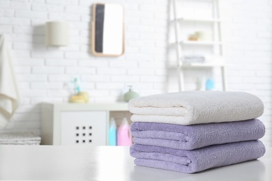 Photo of Stack of fresh towels on table in bathroom. Space for text