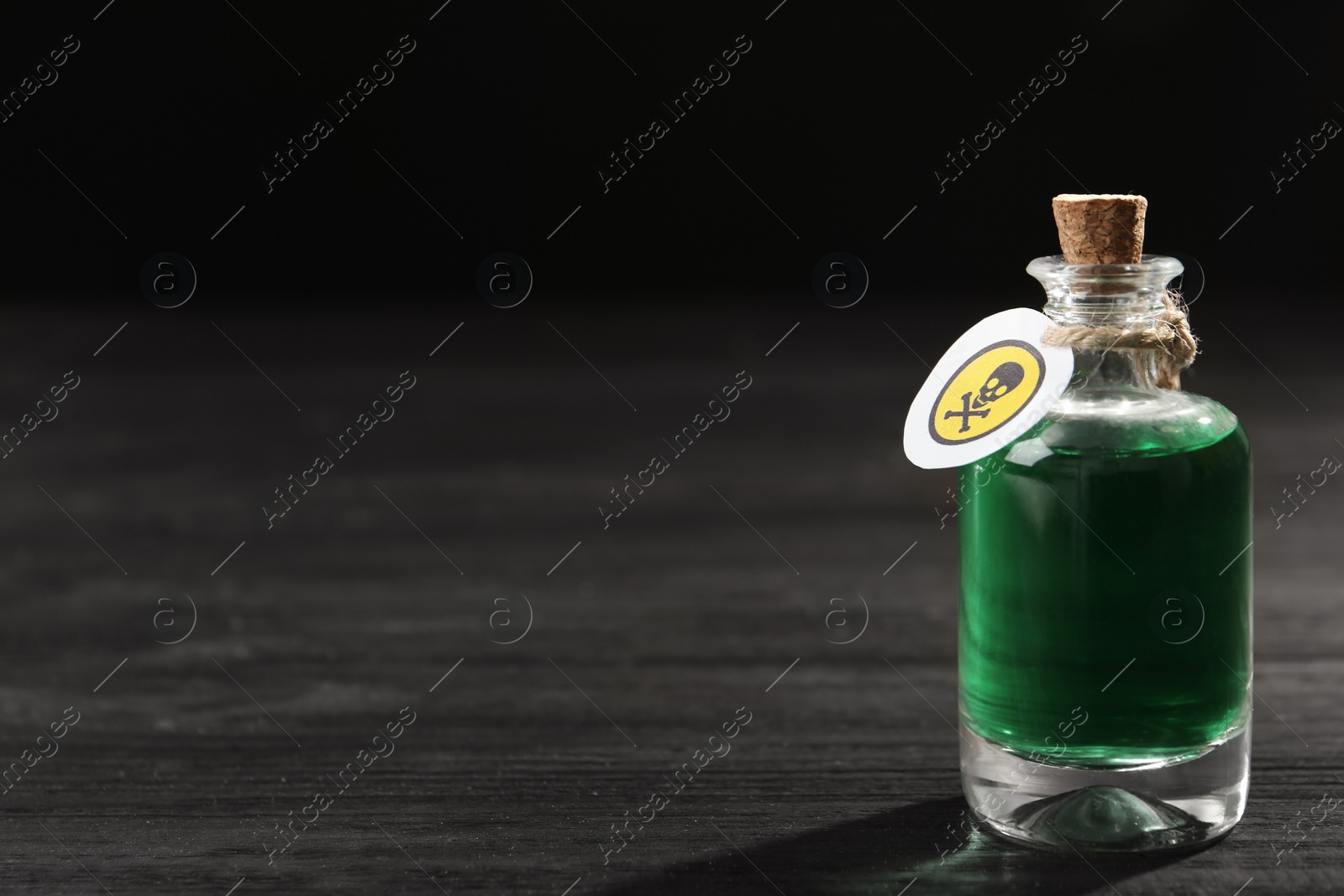 Photo of Bottle with poison on black wooden table. Space for text