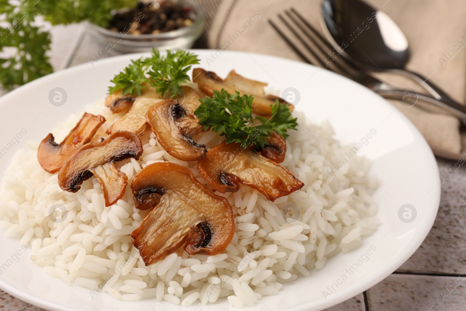 Photo of Delicious rice with parsley and mushrooms on table, closeup