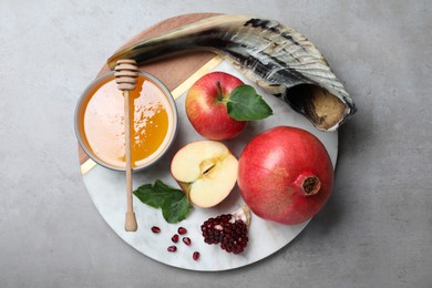 Photo of Honey, pomegranate, apples and shofar on grey table, top view. Rosh Hashana holiday