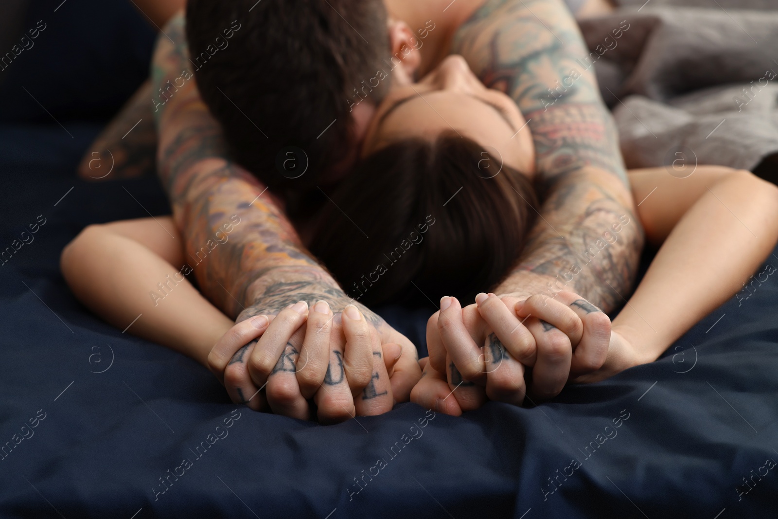 Photo of Passionate couple having sex on bed, focus on hands