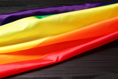 Rainbow LGBT flag on black wooden background, closeup