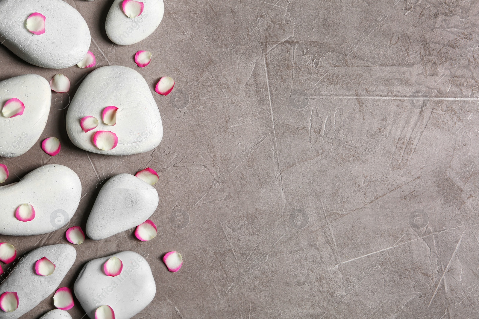 Photo of Flat lay composition with spa stones and flower petals on grey background. Space for text