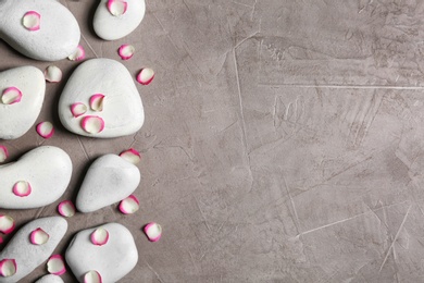 Flat lay composition with spa stones and flower petals on grey background. Space for text