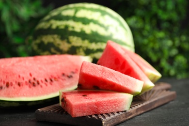 Photo of Whole and cut ripe watermelons on black table