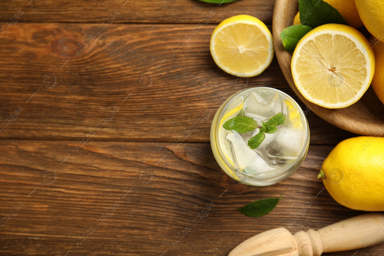 Photo of Cool freshly made lemonade, reamer and fruits on wooden table, flat lay. Space for text