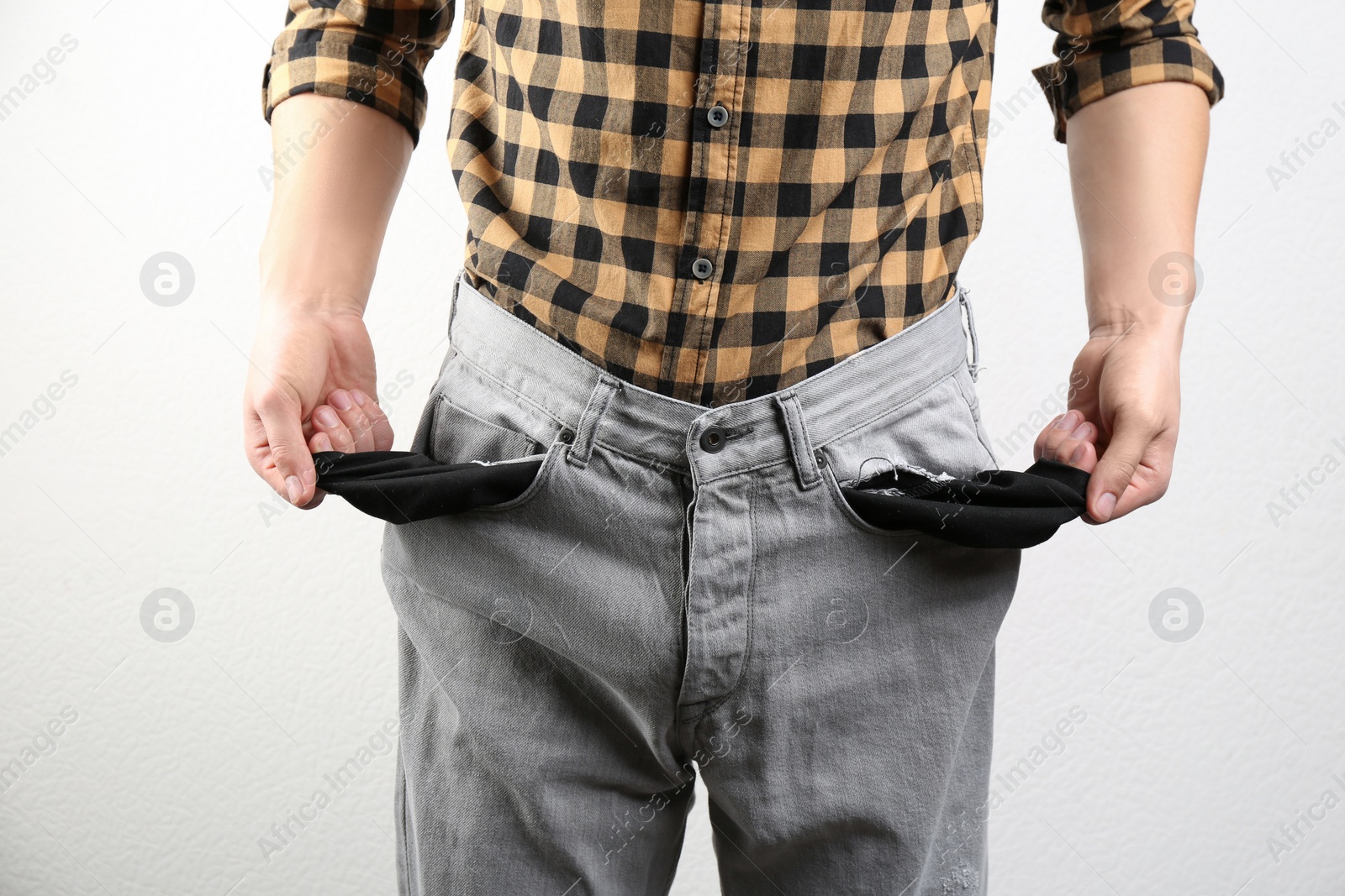 Man showing empty pockets on light background, closeup Photo of Man showing empty pockets on light background, closeup