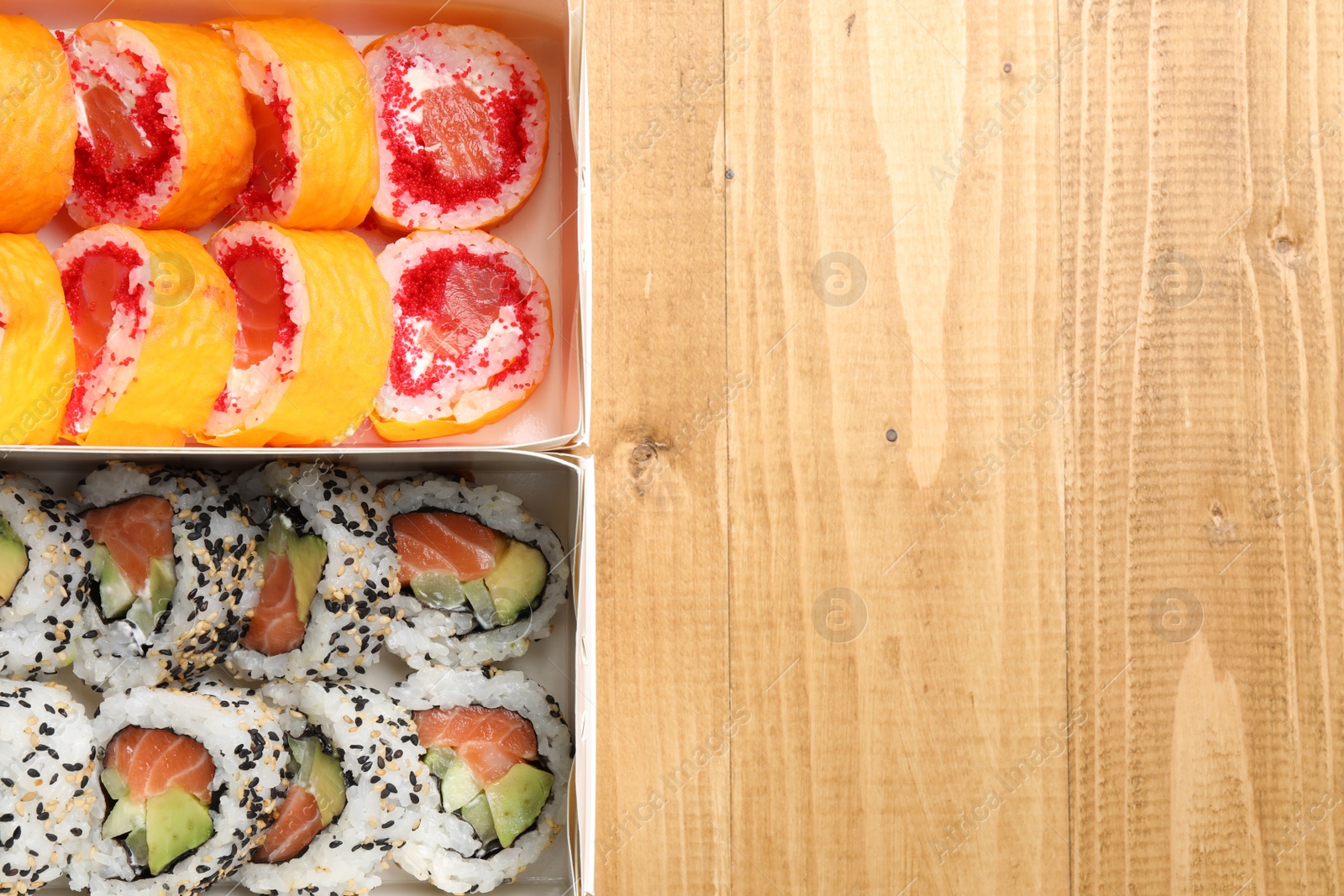 Photo of Food delivery. Paper boxes with delicious sushi rolls on wooden table, flat lay and space for text