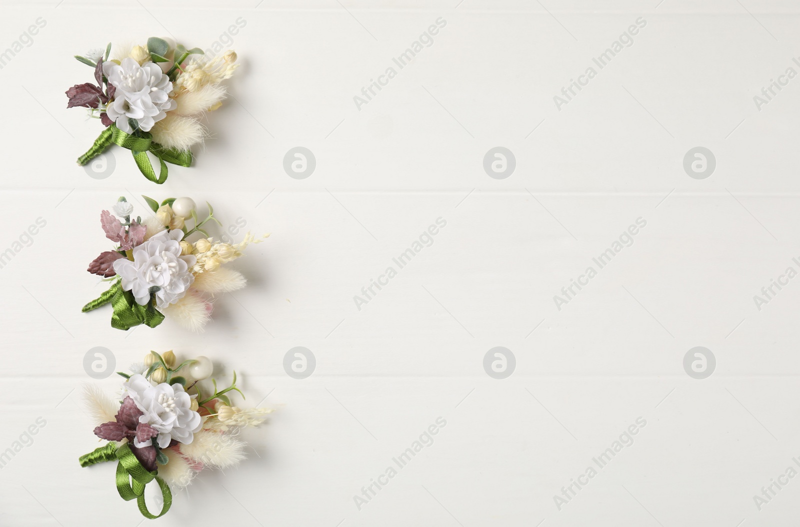 Photo of Beautiful boutonnieres on white background, flat lay. Space for text