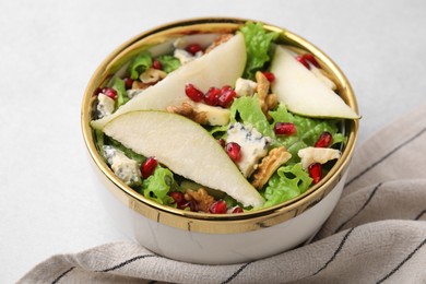 Photo of Delicious pear salad in bowl on light table, closeup