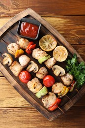 Photo of Delicious shish kebabs with grilled vegetables served on wooden table, top view