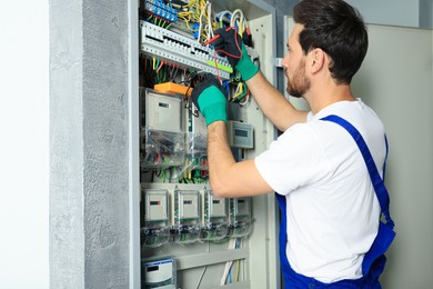 Photo of Electrician checking electric current with multimeter indoors