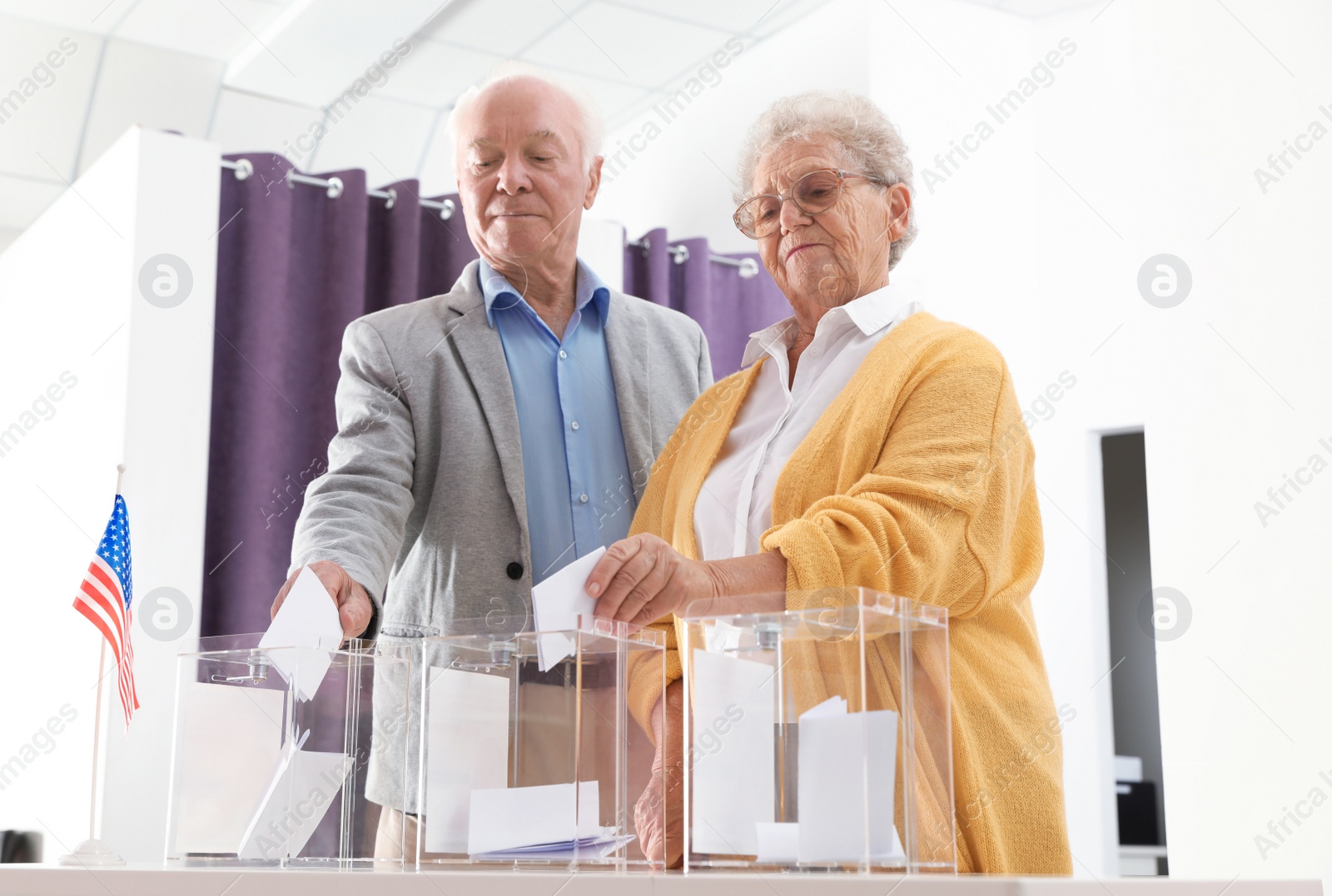 Photo of Elderly people putting ballot papers into boxes at polling station