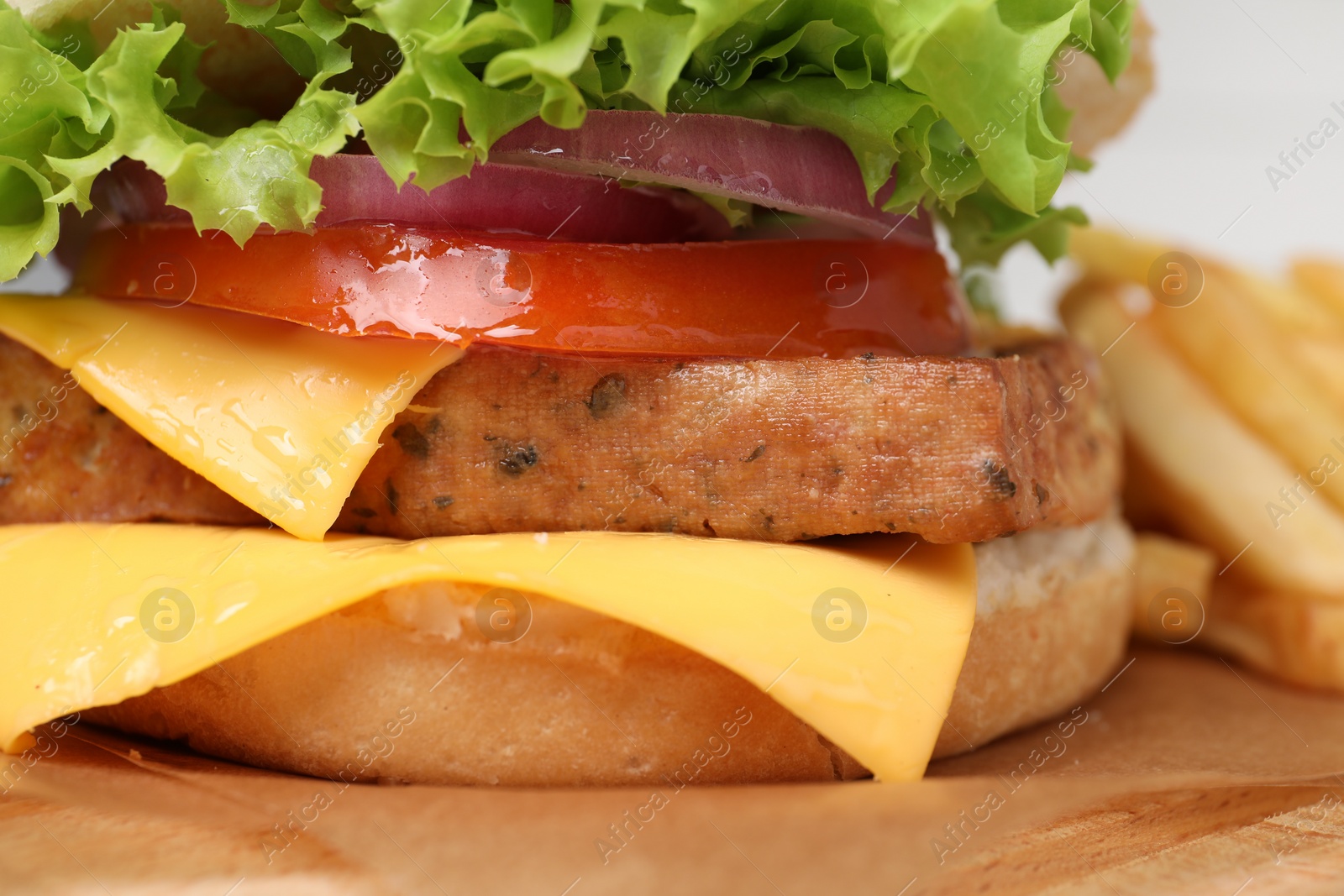 Photo of Delicious burger with tofu and fresh vegetables on wooden table, closeup