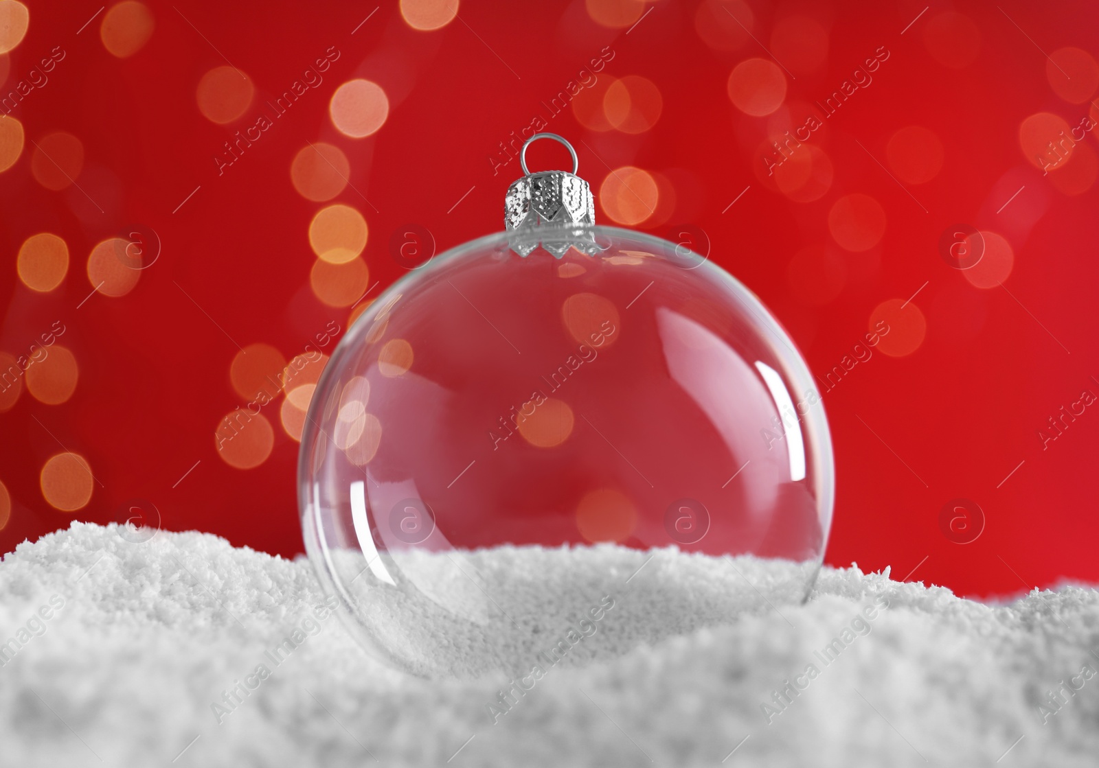 Photo of Transparent Christmas ball on snow against blurred fairy lights