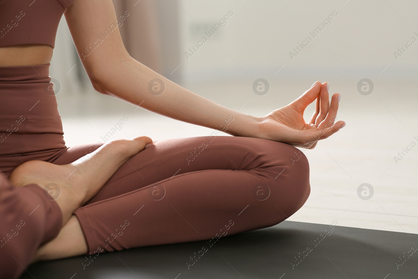 Photo of Woman in sportswear meditating indoors, closeup view