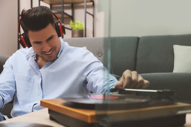 Photo of Happy man listening to music with turntable at home