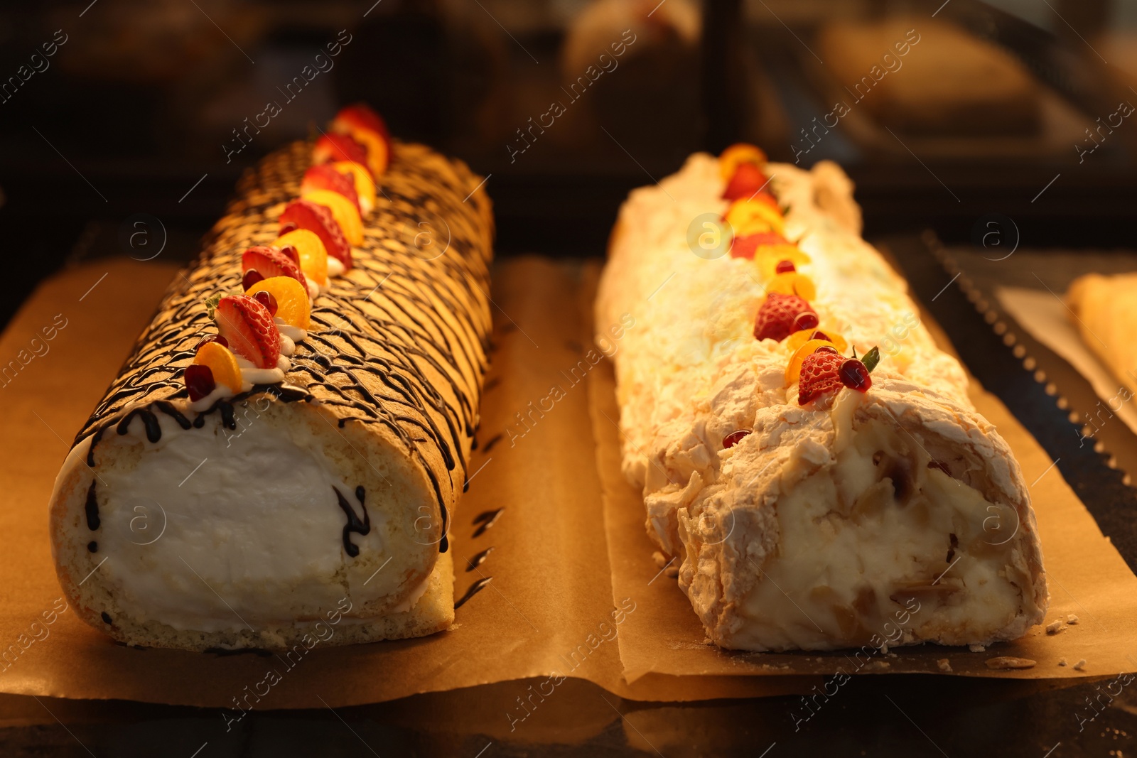 Photo of Delicious cake and meringue rolls on counter in bakery shop, closeup