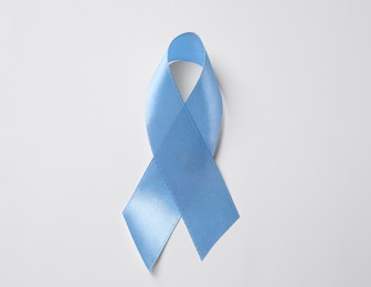 International Psoriasis Day. Light blue ribbon as symbol of support on white background, top view